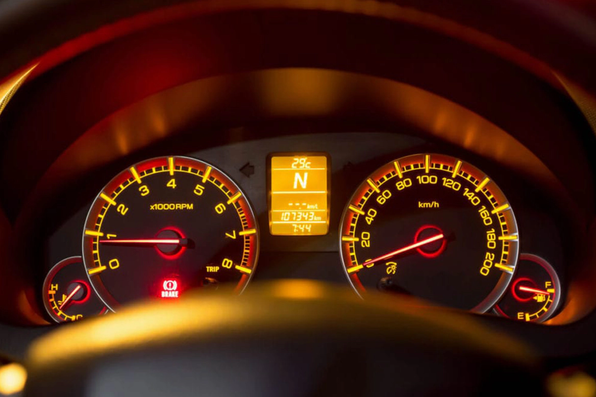 car speedmeter and tachometer illuminated at night with the emergency brake light on